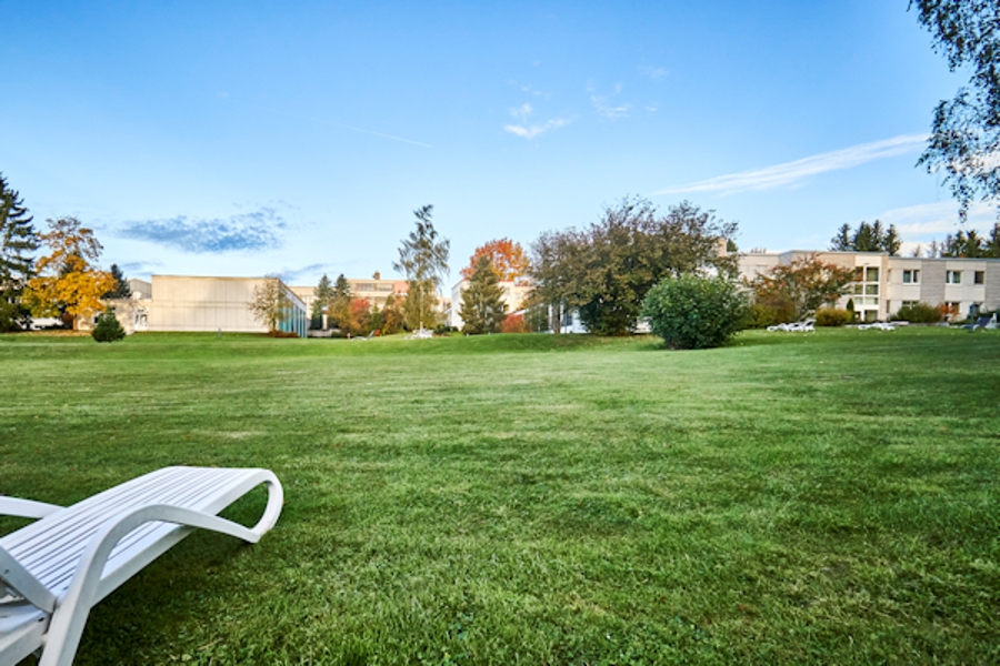 Wiese mit Liegen im Hintergrund das Klinikgebäude umrahmt von Bäumen Wiese mit Liegen im Hintergrund das Klinikgebäude umrahmt von Bäumen